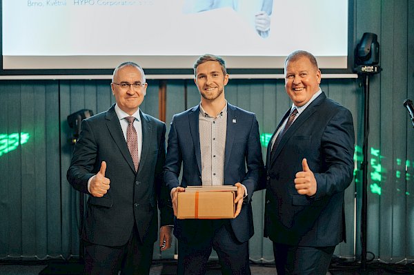 Daniel Kyjonka po převzetí ocenění, vedle něj dva muži v saku s palcem nahoru